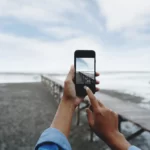 A person takes please a landscape photograph with an iPhone.