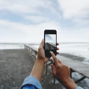 A person takes please a landscape photograph with an iPhone.