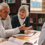 Three adults discuss a play they are reading in a library.