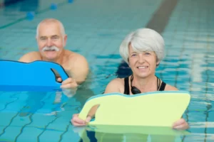 A woman and a man look happy exercising in a swimming pool.