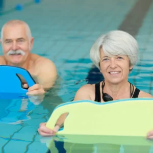 A woman and a man look happy exercising in a swimming pool.