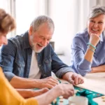 Adults are sitting at a table enjoying board games together.