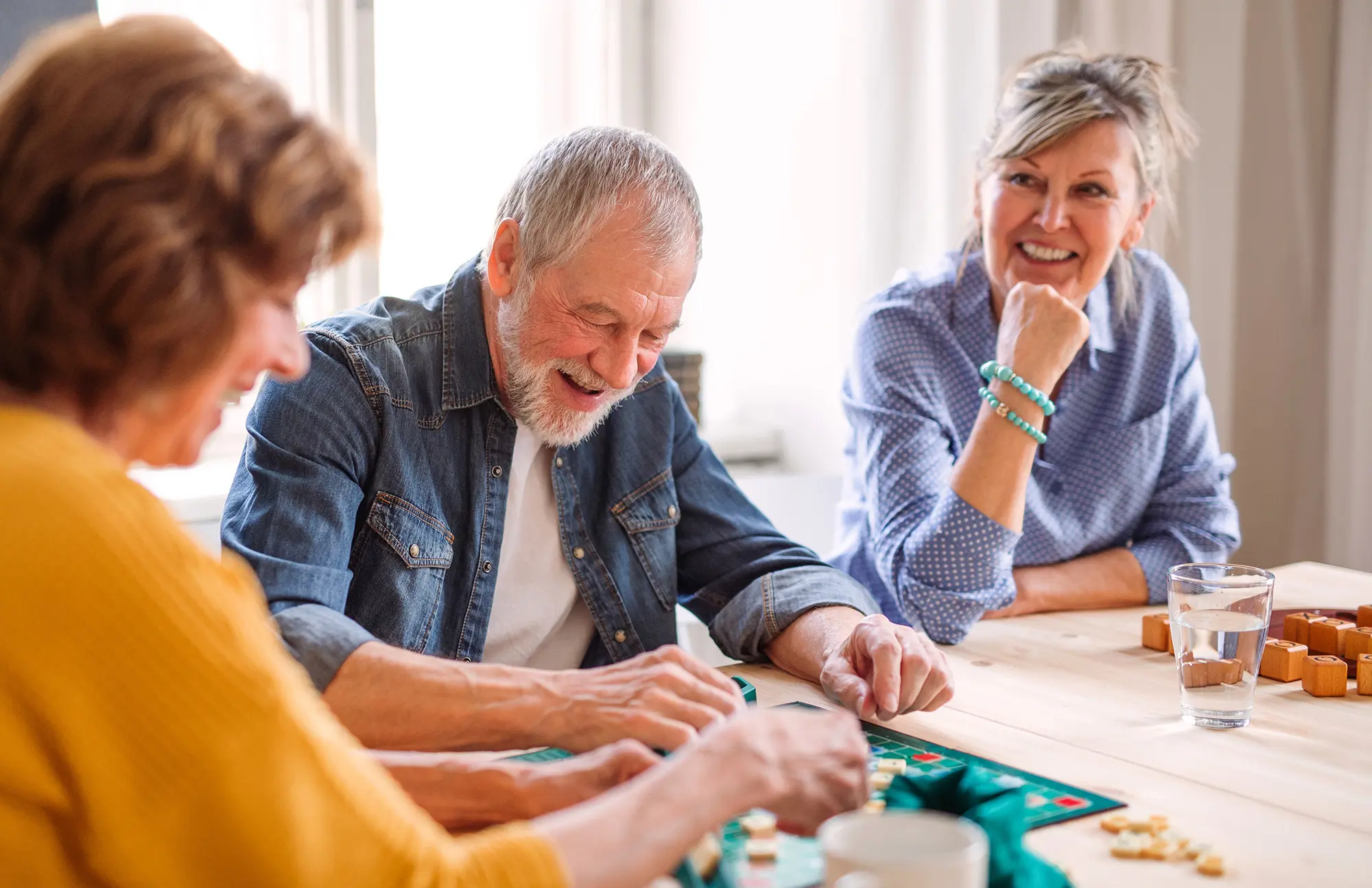 Adults are sitting at a table enjoying board games together.