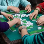 Four people sit around a square table playing mahjong.