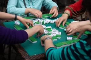 Four people sit around a square table playing mahjong.